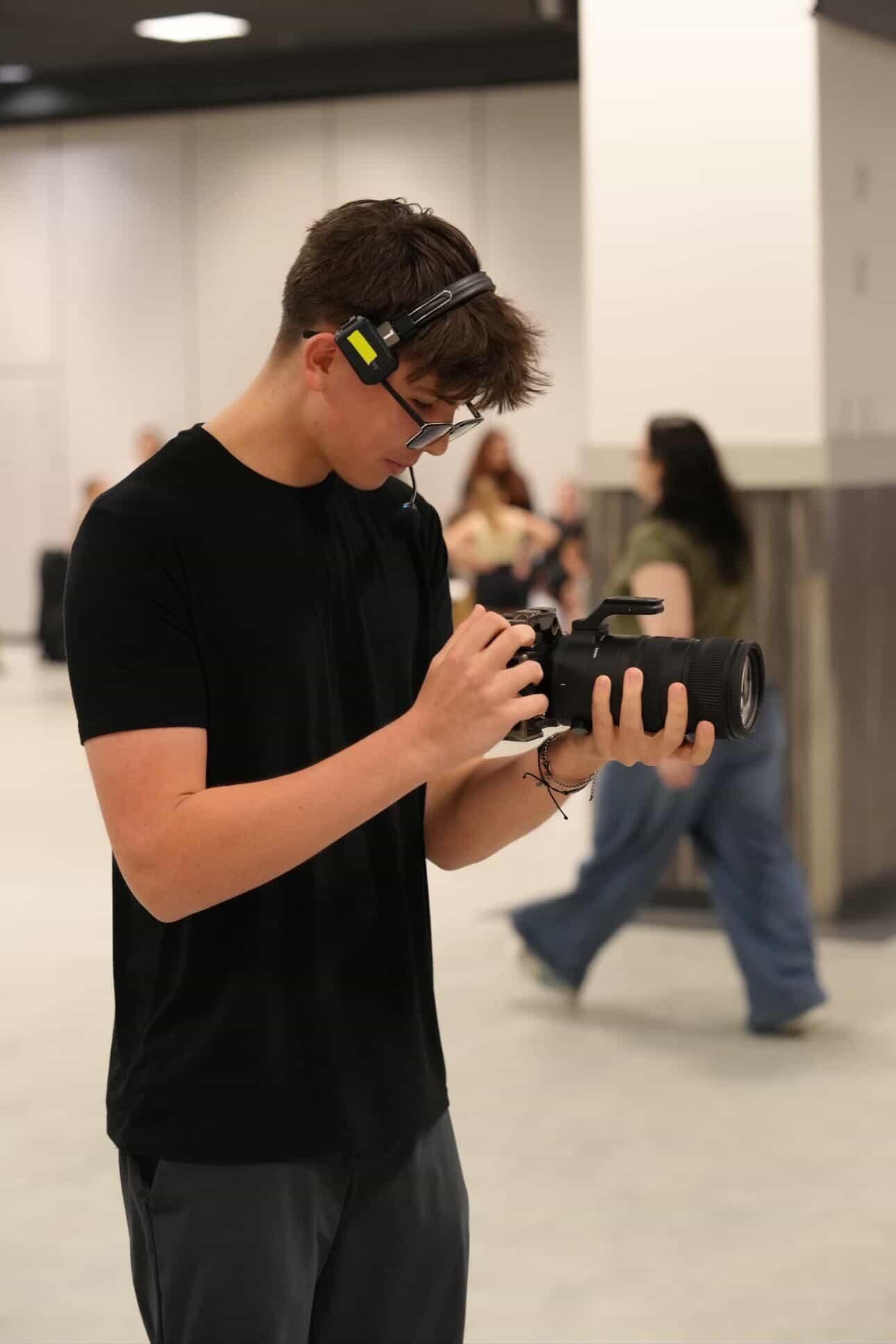 A videographer wearing a headset adjusting a camera on location
